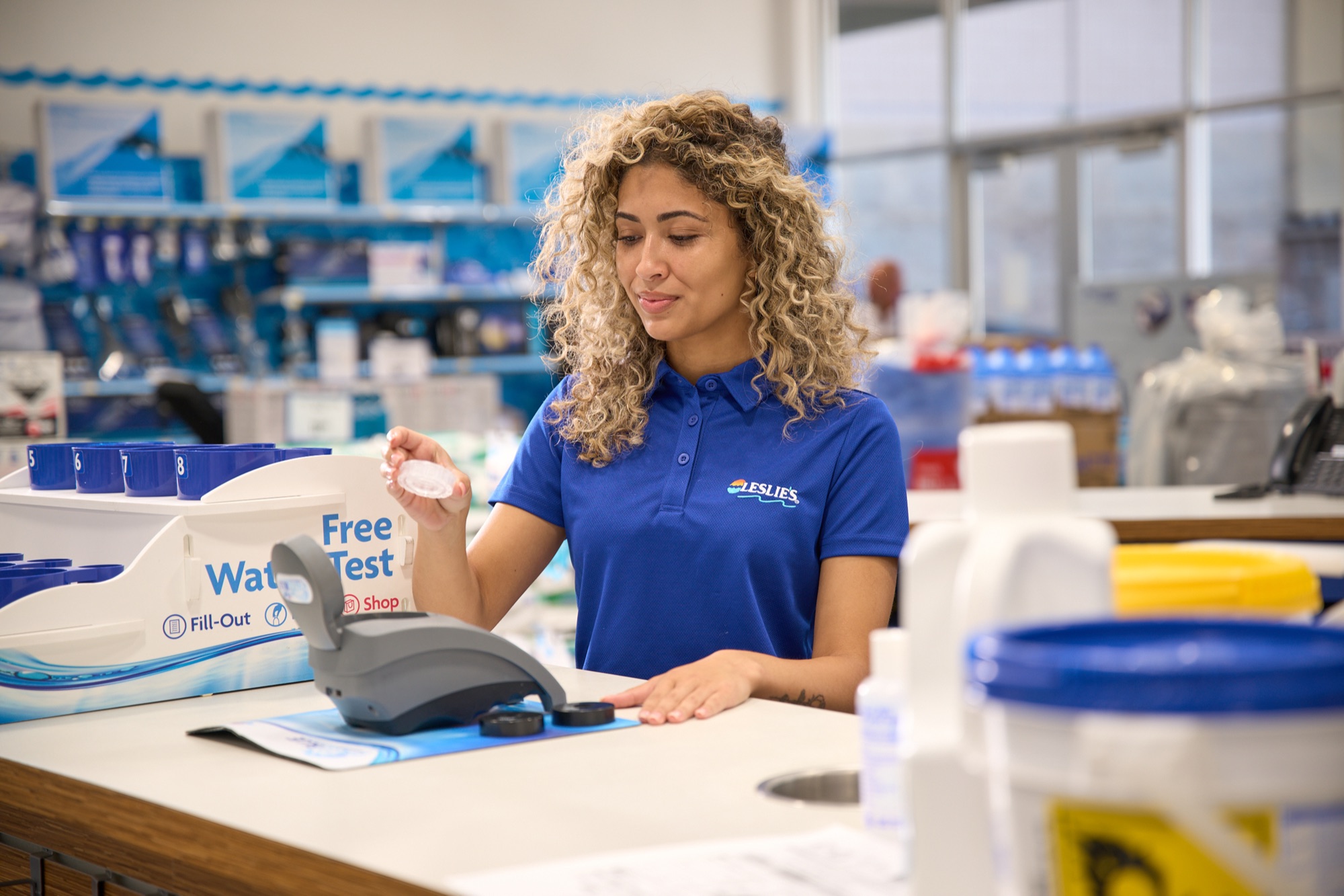 A Leslie's associate running a customer's free in-store AccuBlue water test at the counter